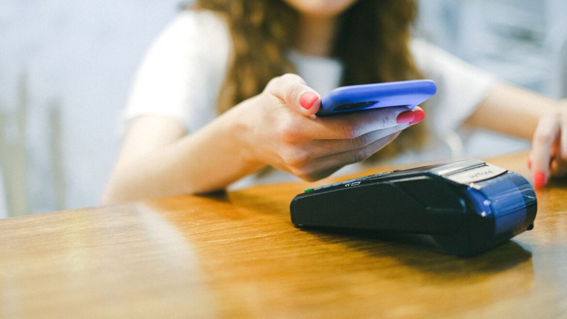Femme effectuant un paiement sans contact avec son smartphone sur un terminal, casino en ligne