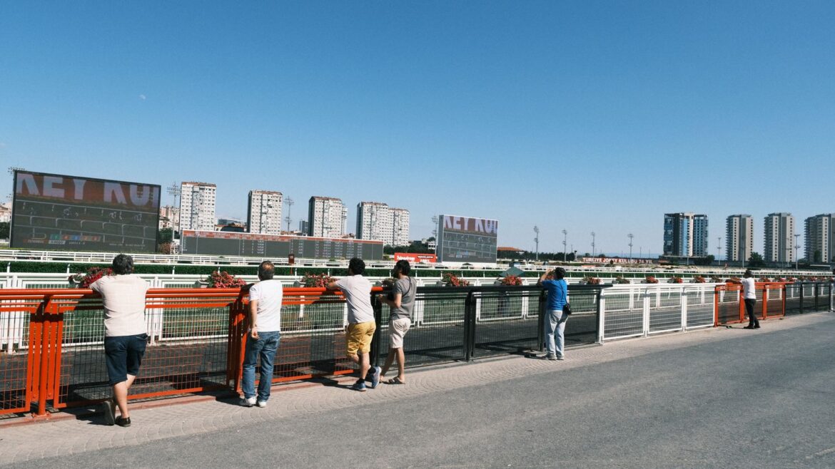 Groupe de parieurs observant une course de chevaux sur un hippodrome urbain