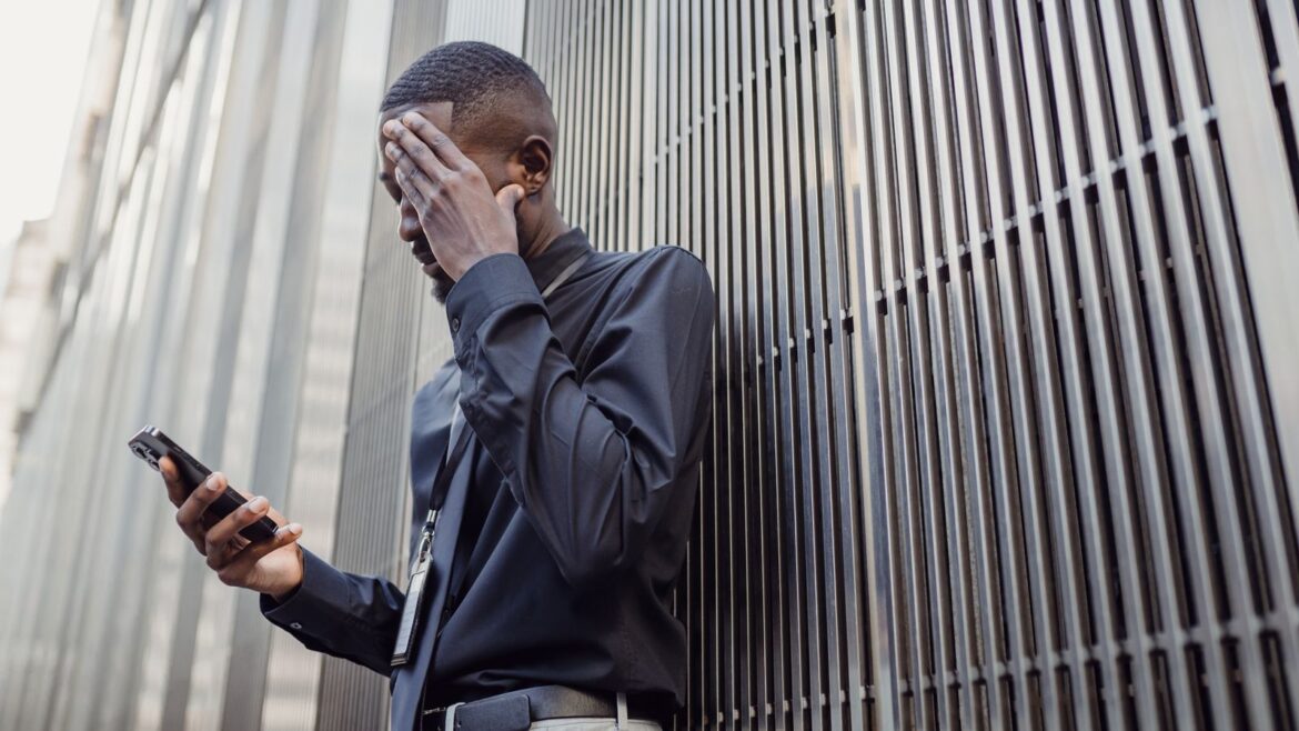 Homme d'affaires en costume utilisant un smartphone devant un immeuble moderne