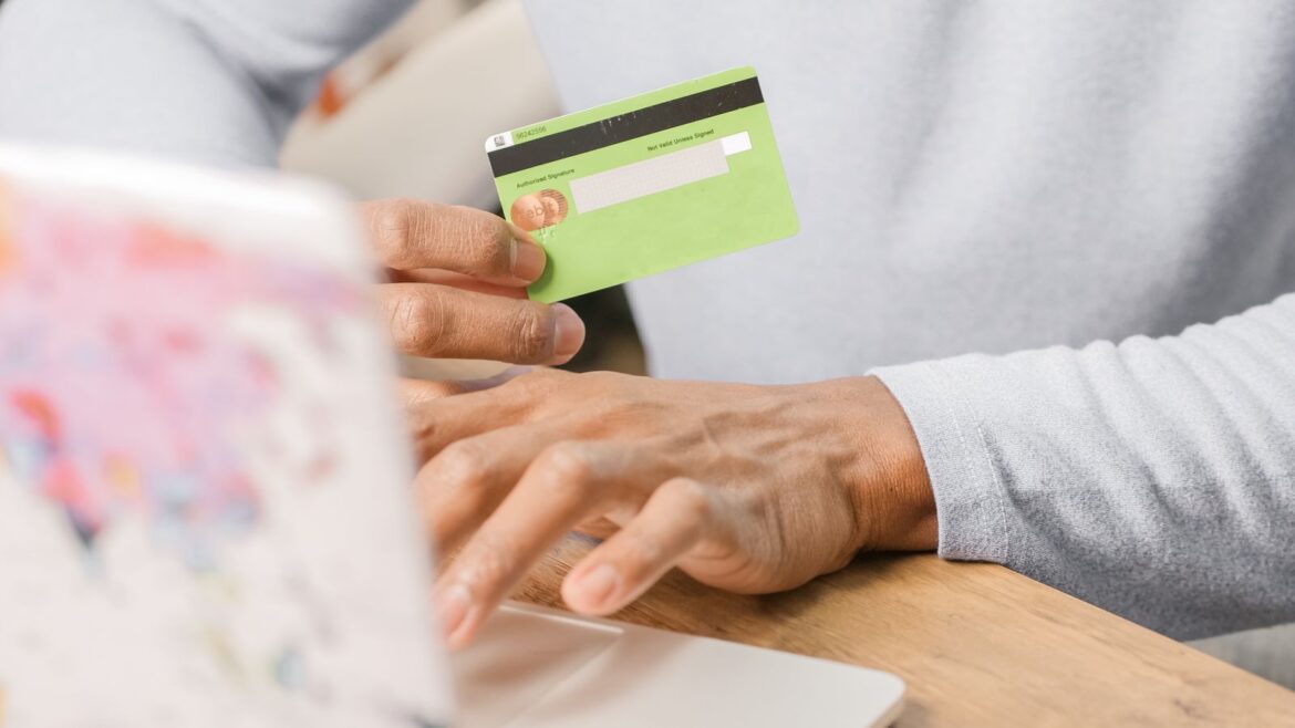 Mains tenant une carte prépayée verte devant un ordinateur portable pour payer sur un casino