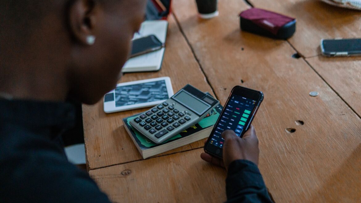 Personne consultant un smartphone avec calculatrice sur table en bois, casino Ethereum